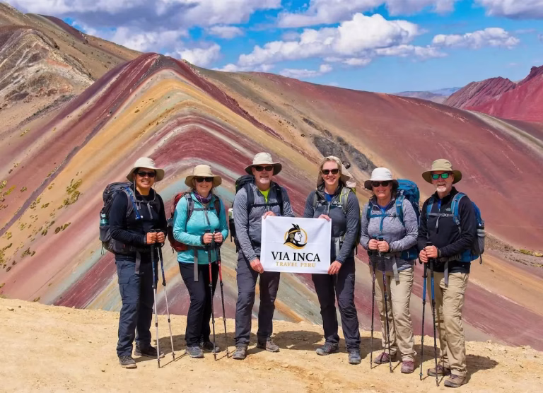 A hiker standing at the 5,036m summit of the 7-color Rainbow Mountain.